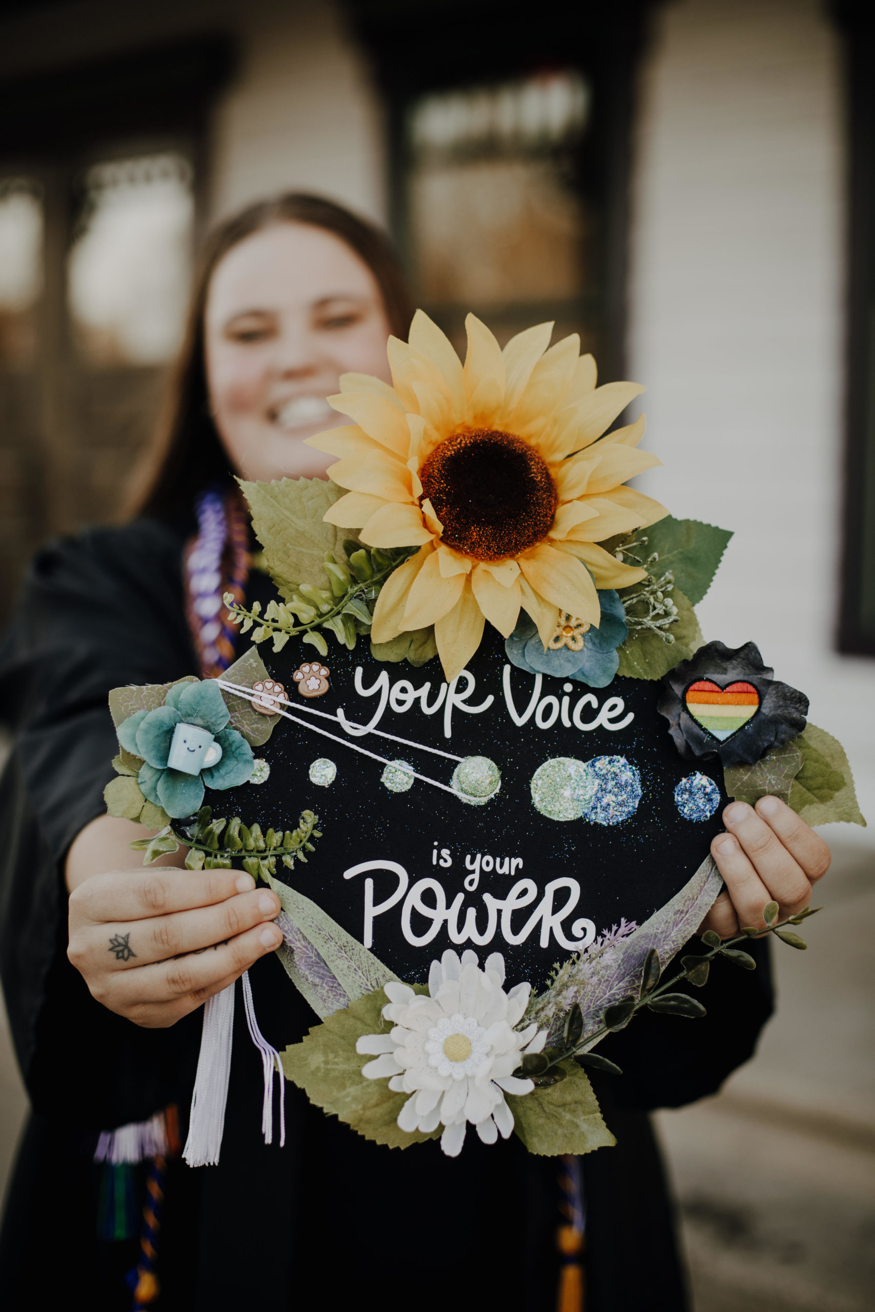 Photo of student holding graduation cap to camera. Cap includes Active Minds logo and text reading "Your Voice is Your Power."