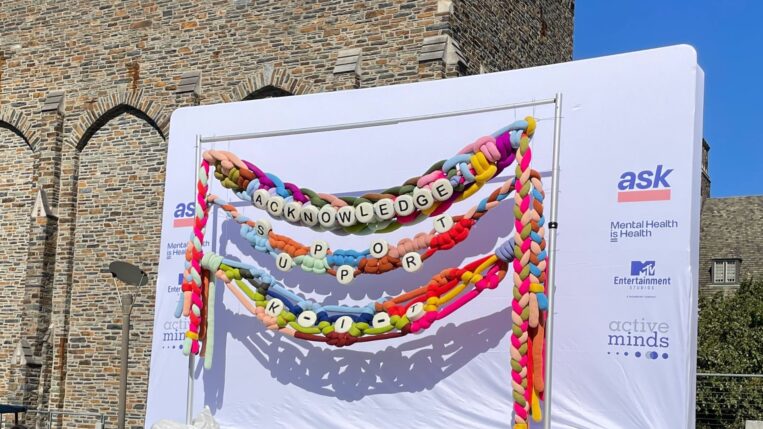 Giant ASK bracelet on display in front of a brick building